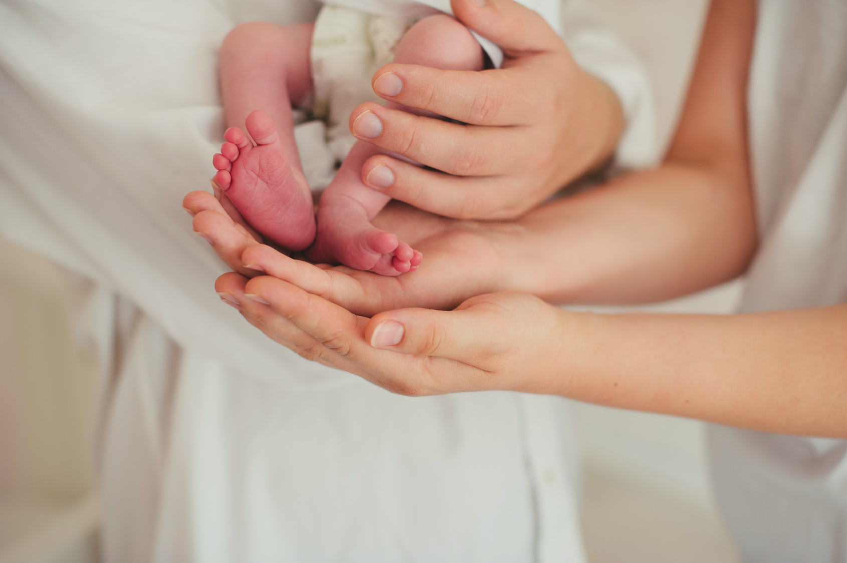 Newborn baby feet on father and mother hands, close-up